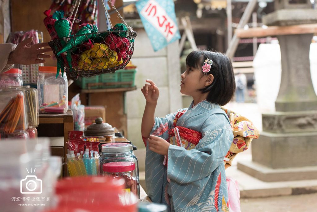 駄菓子屋で買い物をする七五三の女の子